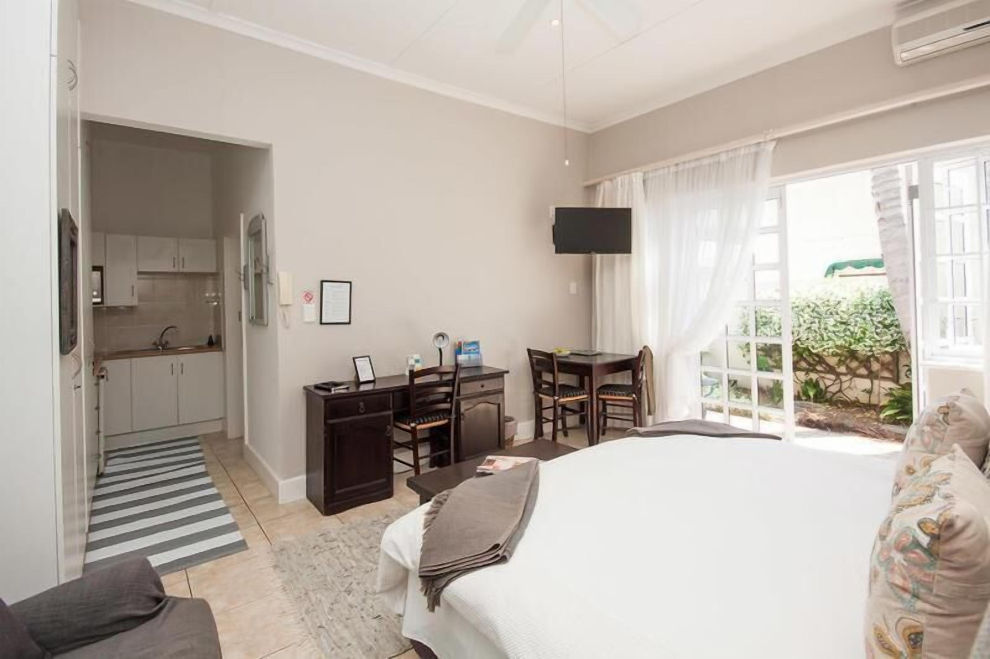 Habitación de hotel con cama, escritorio, silla, televisor y vistas al exterior.