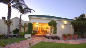 A house with a front porch, palm trees, and a well-maintained lawn. - Anchorage Guest House (Gqeberha (Port Elizabeth))
