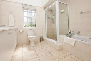 Enjoy a serene bathroom retreat with a bathtub, glass-enclosed shower, and large window overlooking lush greenery.