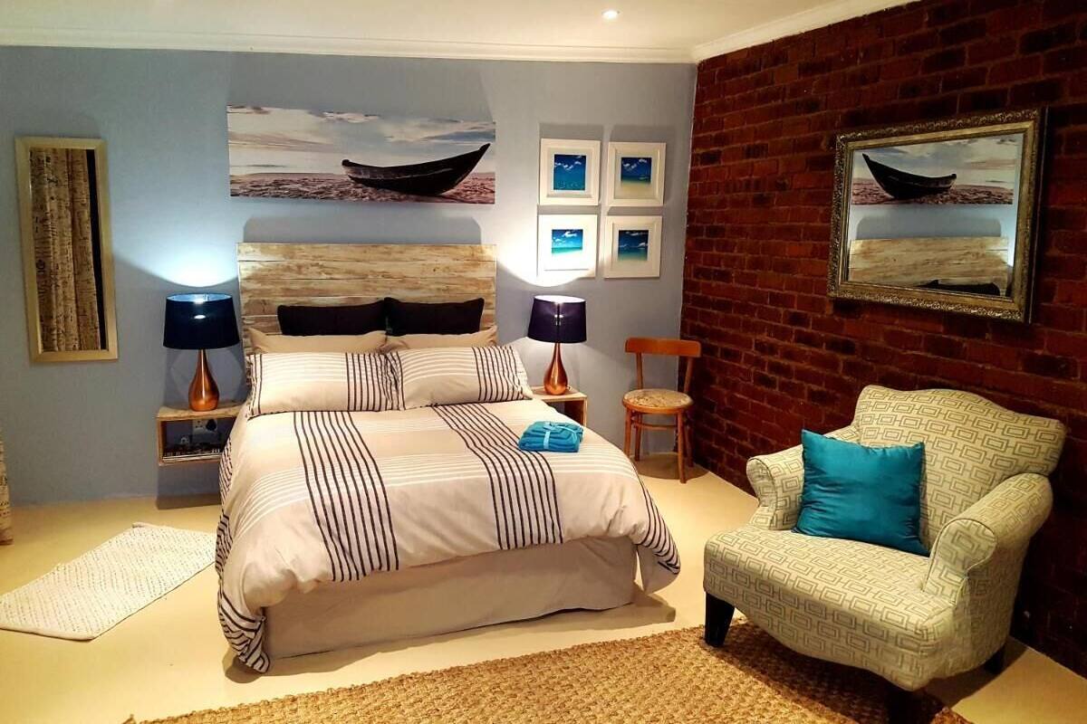 A bedroom with a bed, two bedside tables, a chair, and artwork on the walls.