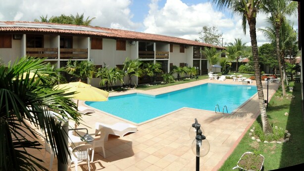 Ein Hotel mit Pool, Sitzgelegenheiten im Freien und Palmen.