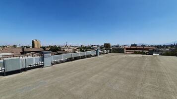 A rooftop terrace with a clear view of the city skyline, including buildings and mountains in the distance.