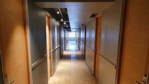 Un pasillo largo y estrecho con puertas a ambos lados y piso de baldosas.