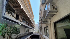 Un estrecho pasillo con balcones, unidades de aire acondicionado y piso de baldosas.