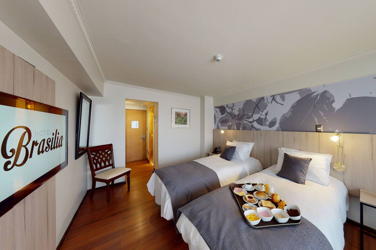 Habitación de hotel con dos camas, una bandeja de desayuno, una silla y un cartel en la pared.