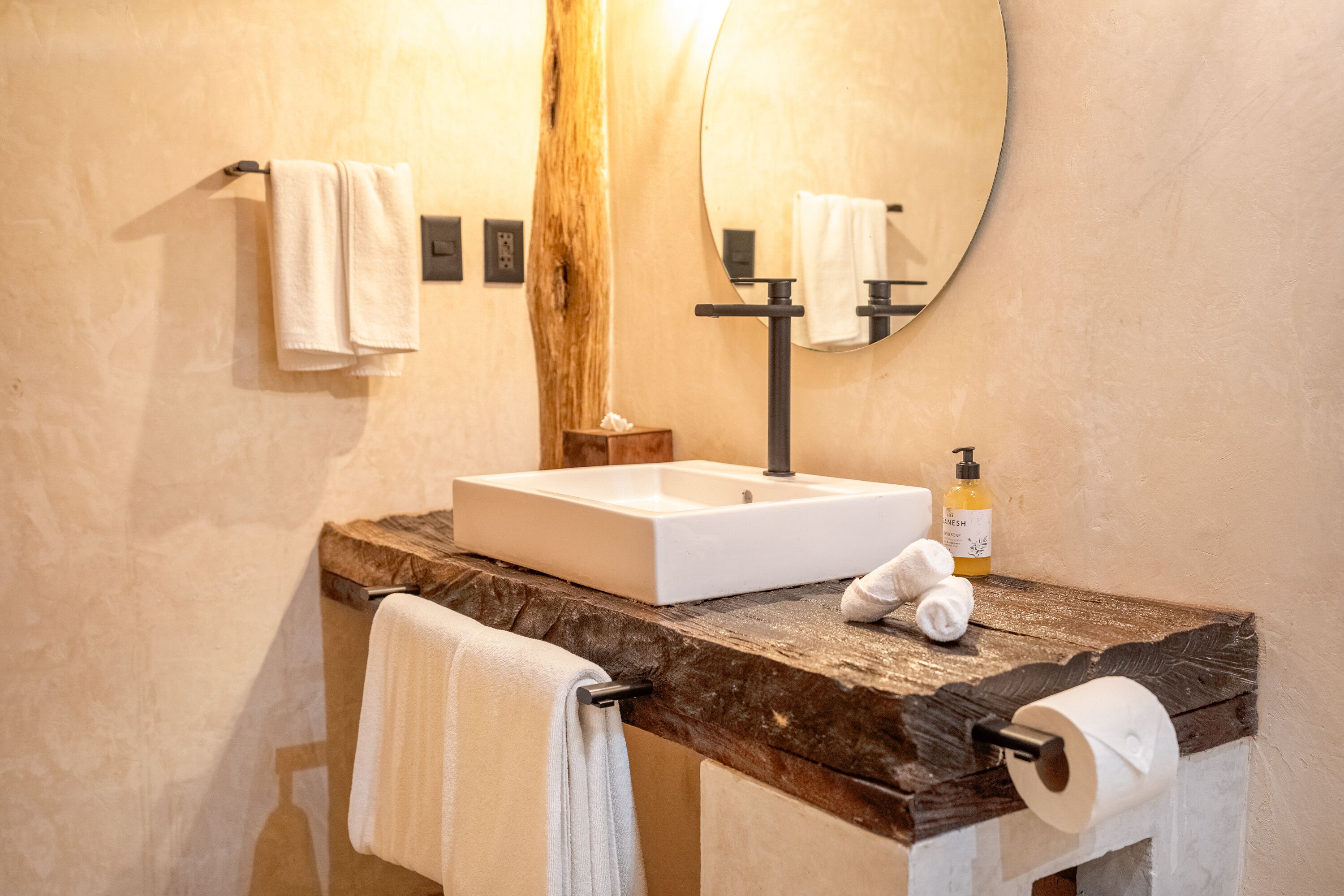 A bathroom with a wooden countertop, a white sink, a mirror, and two towels.