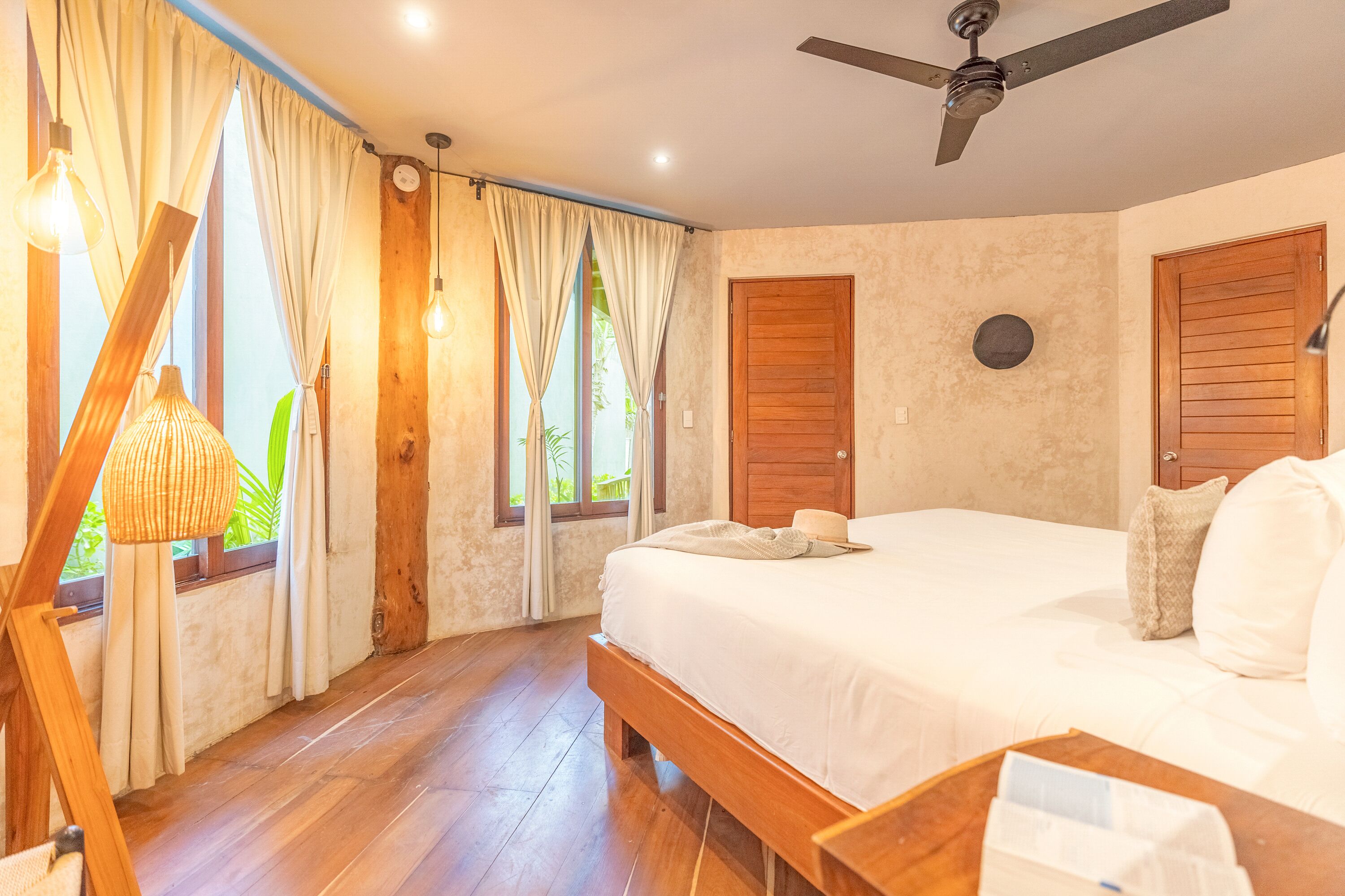 A bedroom with a wooden bed, a ceiling fan, and curtains.