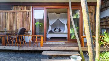 Una terraza de madera con una cama con dosel, un banco y una mesita.