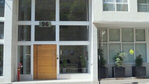 A modern building with large windows and a wooden door, numbered 96. - Apartamentos San Isidro (Santiago)