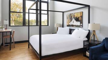 Quarto moderno com cama de dossel, escrivaninha, cadeira, luminária e um quadro na parede.