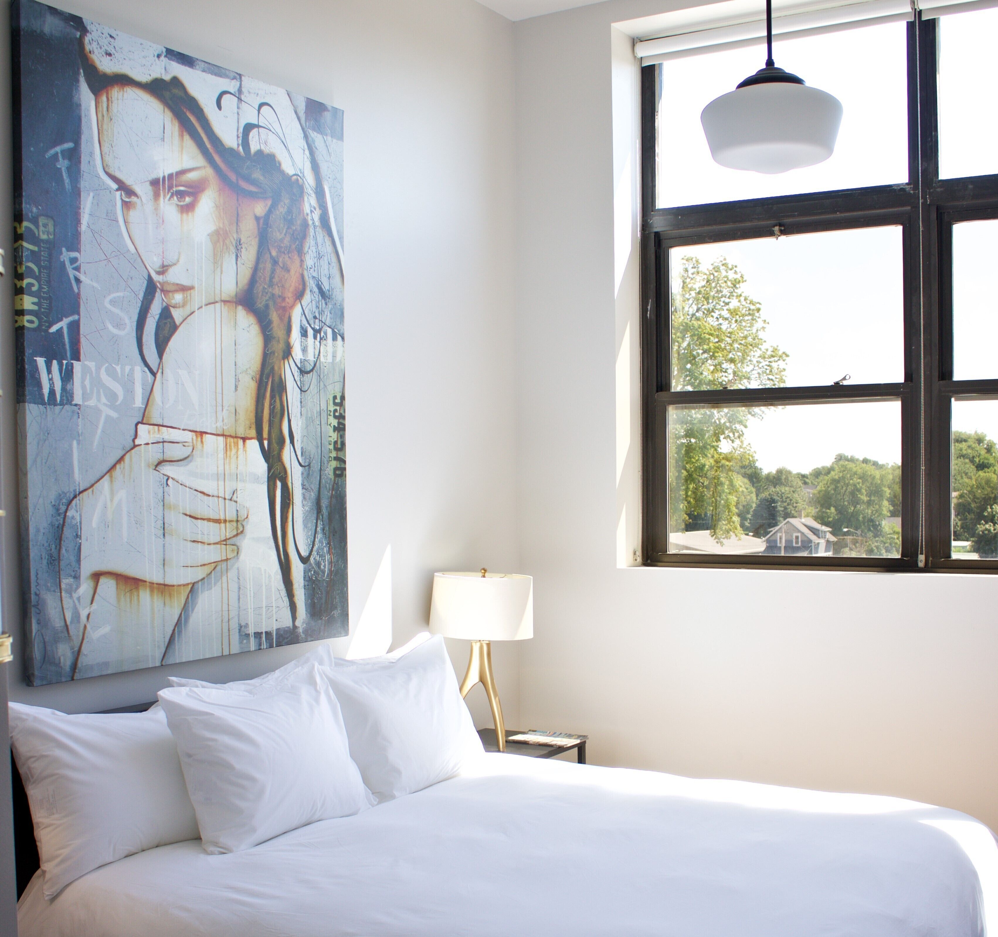 Un dormitorio con una cama grande, una ventana con vistas a árboles y un cuadro colgado en la pared.