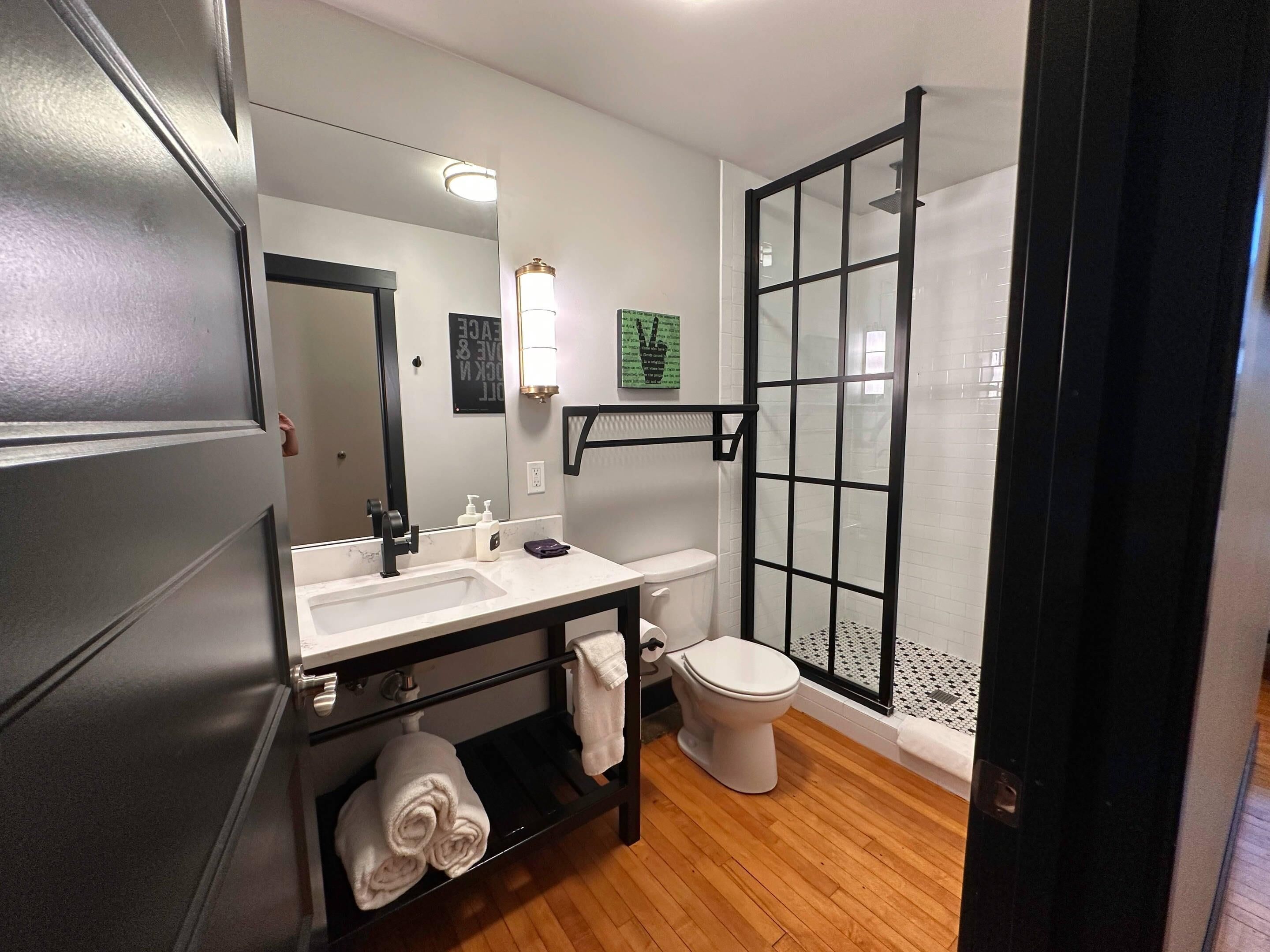 A modern bathroom with a sink, toilet, and walk-in shower.