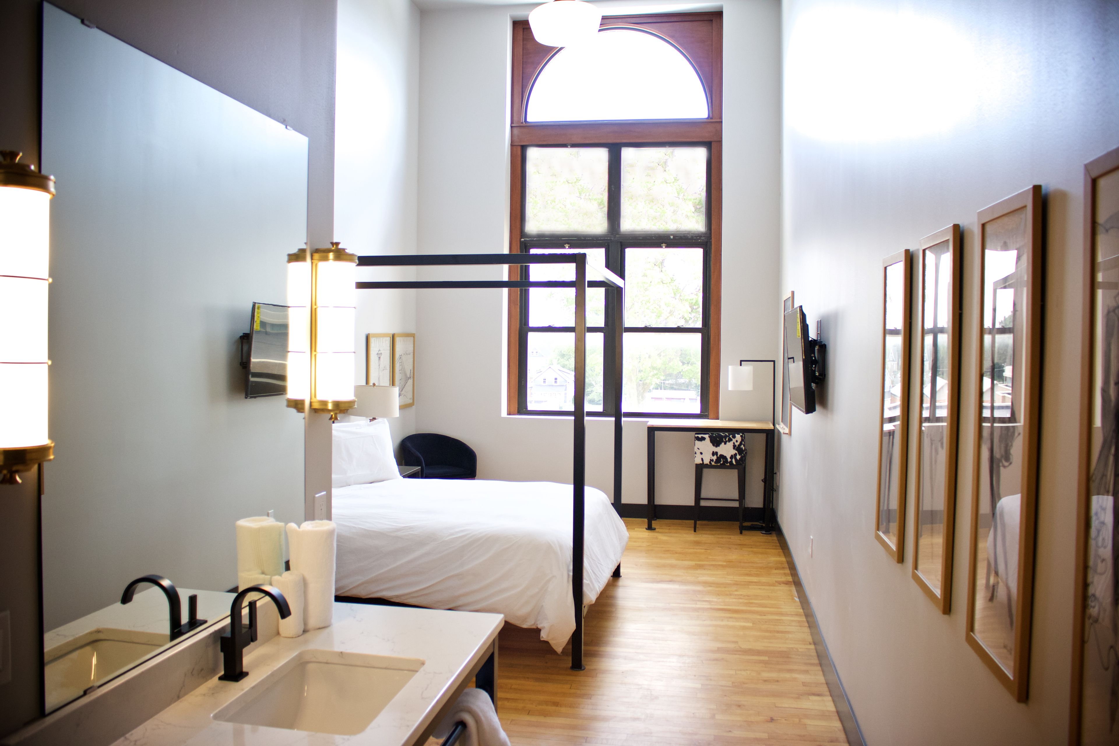 Habitación de hotel con una cama grande, un baño con lavabo y espejo, un escritorio y una ventana con vistas.