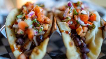Two tacos with a filling of beans, tomatoes, and onions.