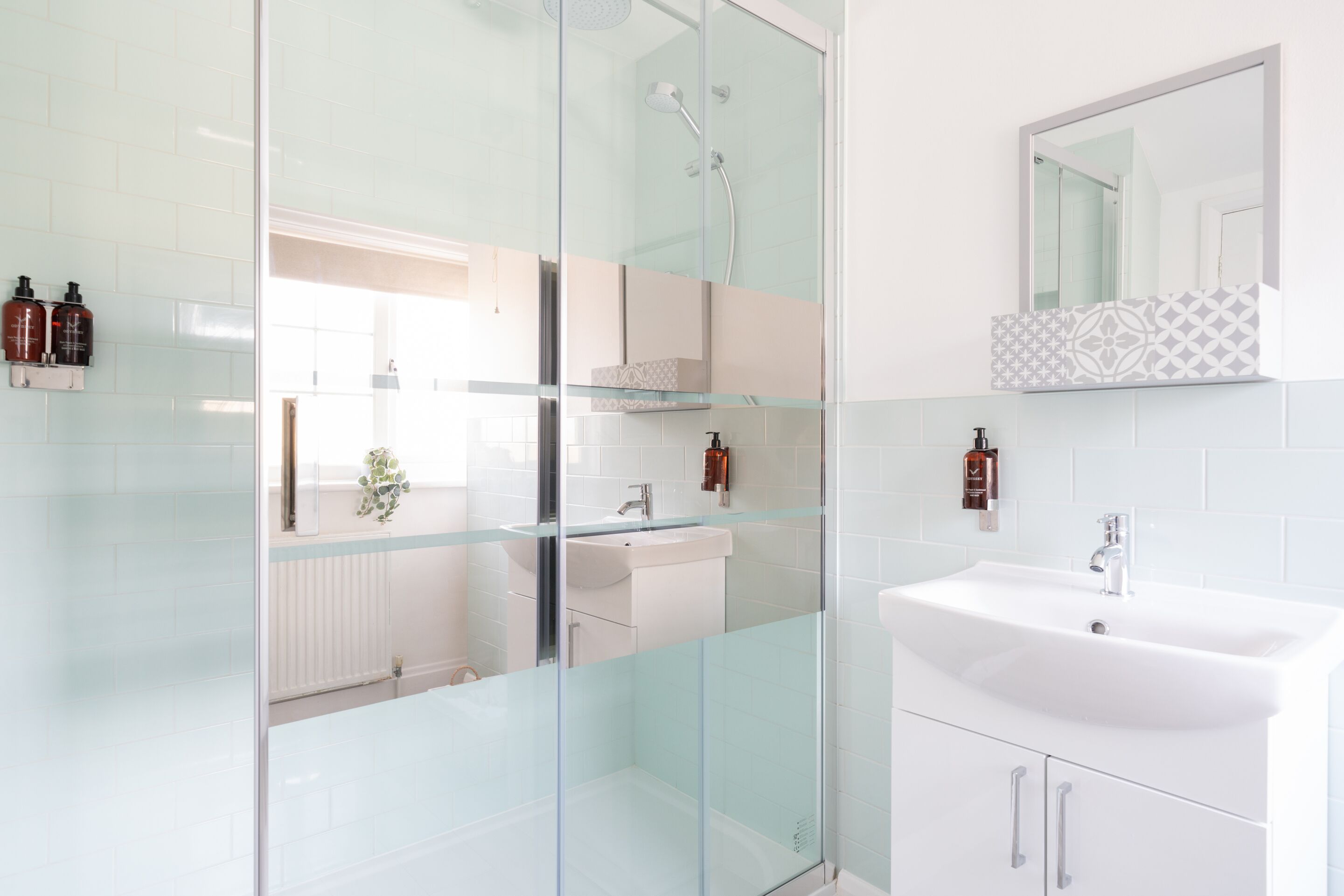 A modern bathroom with a glass shower enclosure, a white sink, and a mirror above the sink.