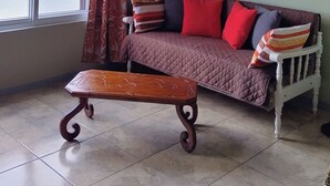 Un soggiorno con divano, tavolino in legno, finestra con tende e decorazioni alle pareti.