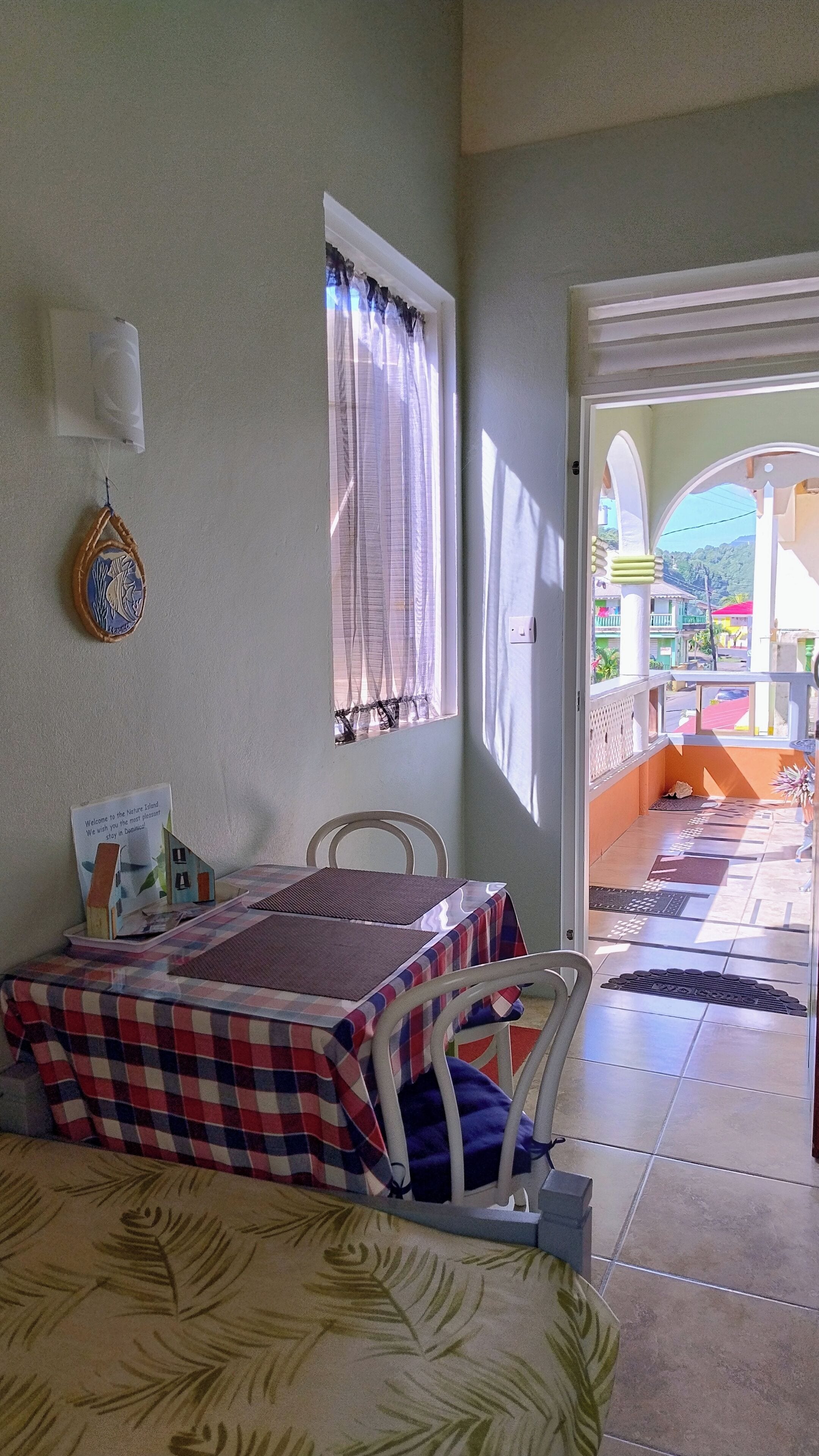 Una habitación con cama, una mesa, una silla, un ventanal con cortinas y vistas al exterior.