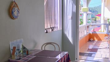 Una habitación con cama, una mesa, una silla, un ventanal con cortinas y vistas al exterior.