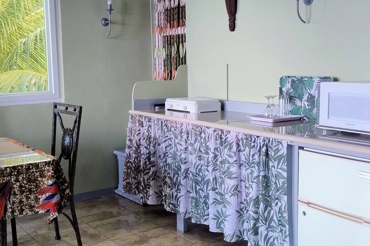 A kitchen with a table, chairs, a refrigerator, and a window.