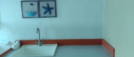 A bathroom with a sink, mirror, and a shelf with toiletries.