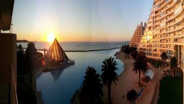 A resort with a pool, beach, and a pyramid structure. - Departamento Fragata (Algarrobo)