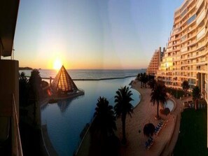 A resort with a pool, beach, and a pyramid structure. - Departamento Fragata (Algarrobo)