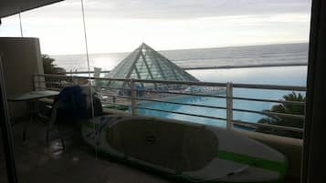 Uma varanda com vista para uma piscina e uma estrutura piramidal de vidro.