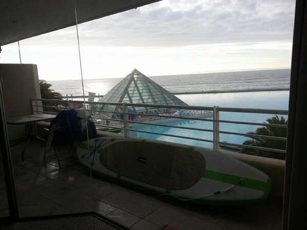 Un balcón con vista a una piscina y una estructura piramidal de vidrio.