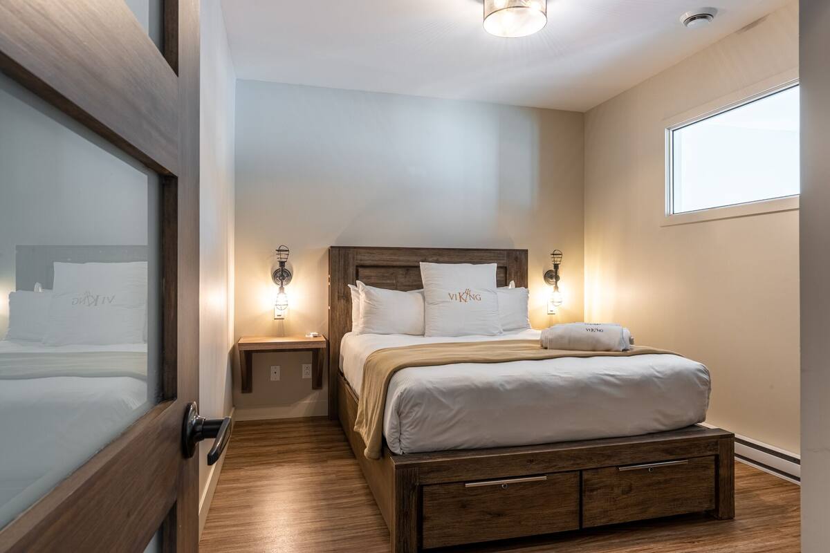 Une chambre à coucher bien rangée, avec un cadre de lit en bois, du linge de lit blanc et deux lampes de chevet.