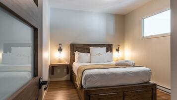 Un dormitorio ordenado con estructura de cama de madera, ropa de cama blanca y dos lámparas de noche.