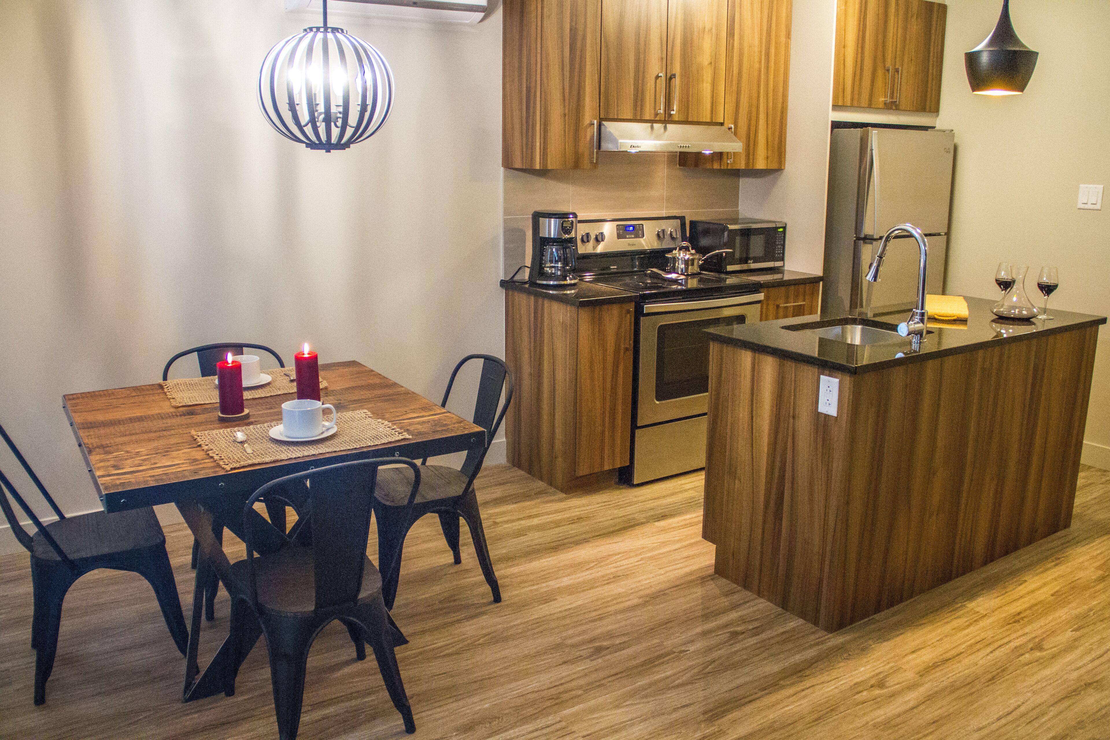 Una cocina moderna con armarios de madera, un refrigerador de acero inoxidable, horno empotrado y cafetera.