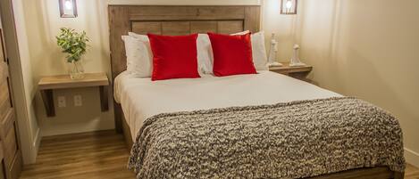 A neatly made bed with a patterned blanket, a wooden headboard, and two bedside tables with lamps.