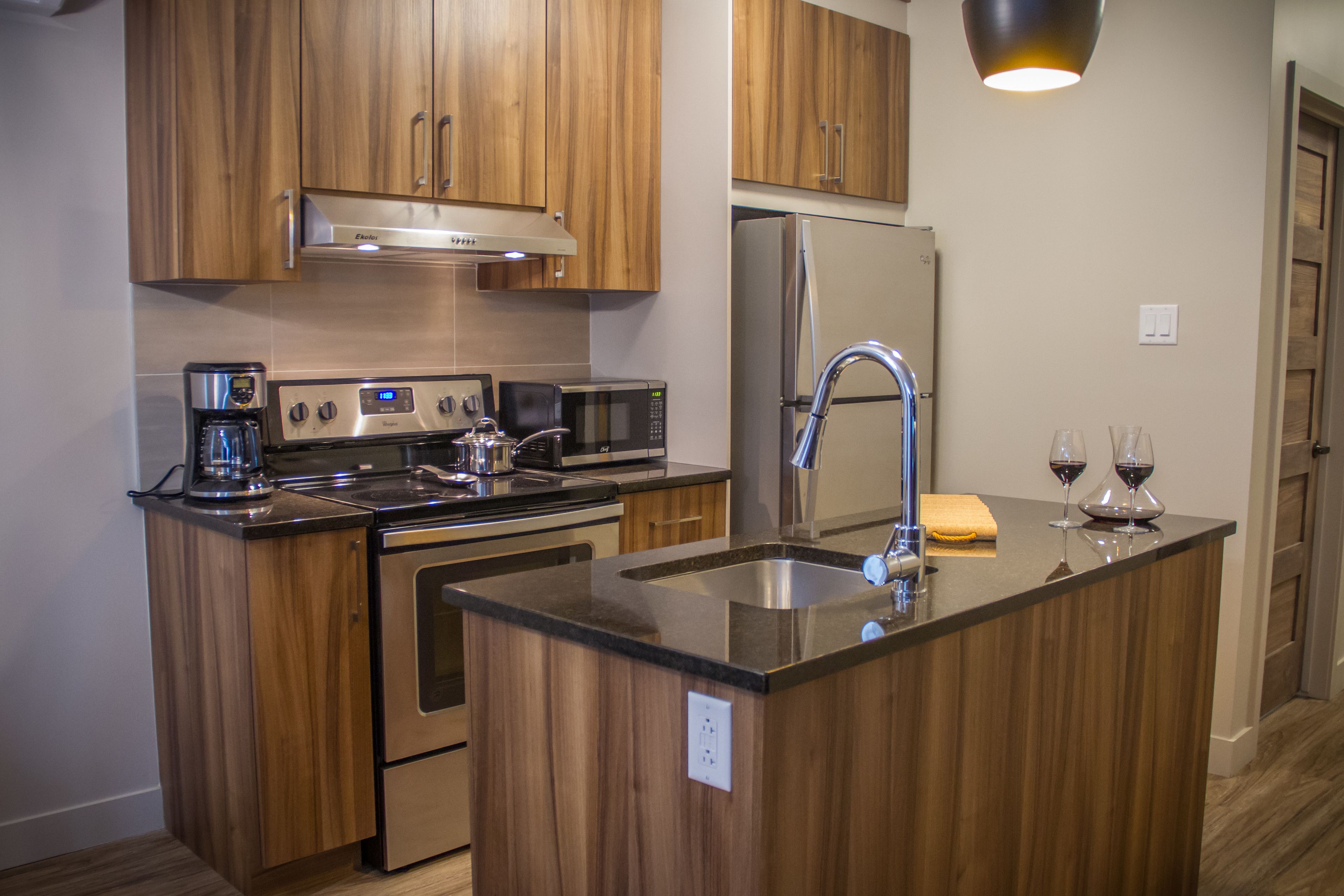 A modern kitchen with wooden cabinets, stainless steel appliances, and a central island with a sink.