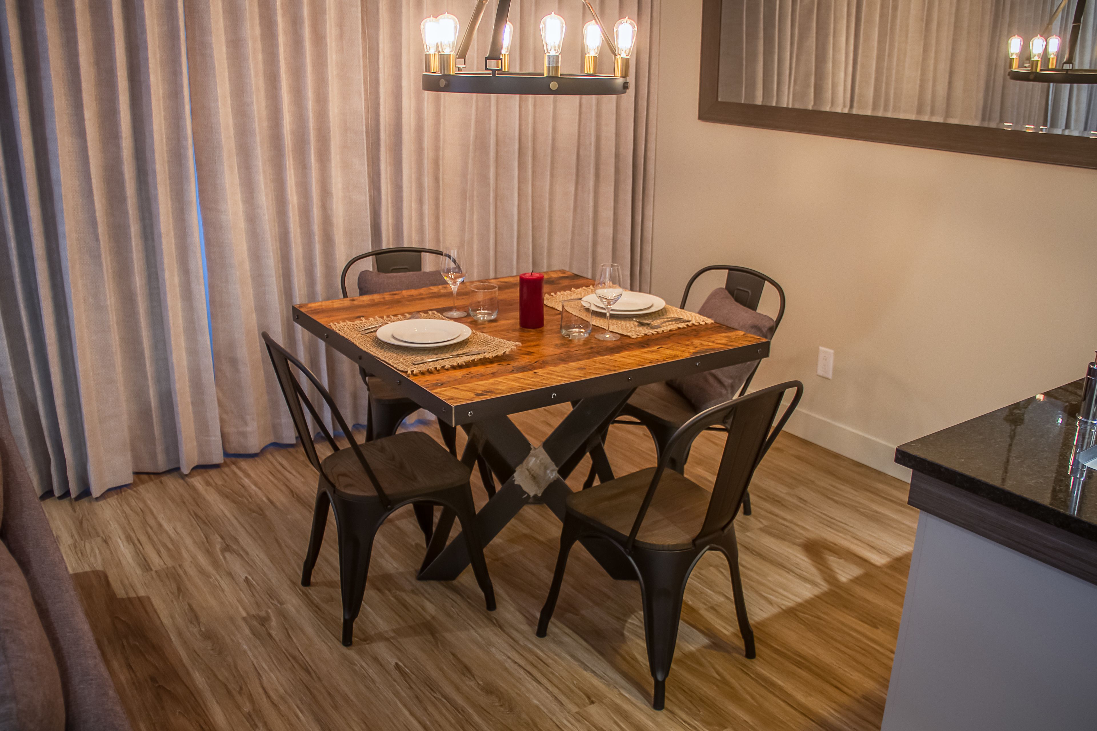 Een eetruimte met een houten tafel, zes stoelen en een kroonluchter.