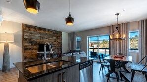 A modern kitchen with a central island, stainless steel appliances, and a rustic wooden accent wall. - Le Viking Resort & Marina (Sainte-Marguerite-du-Lac-Masson)
