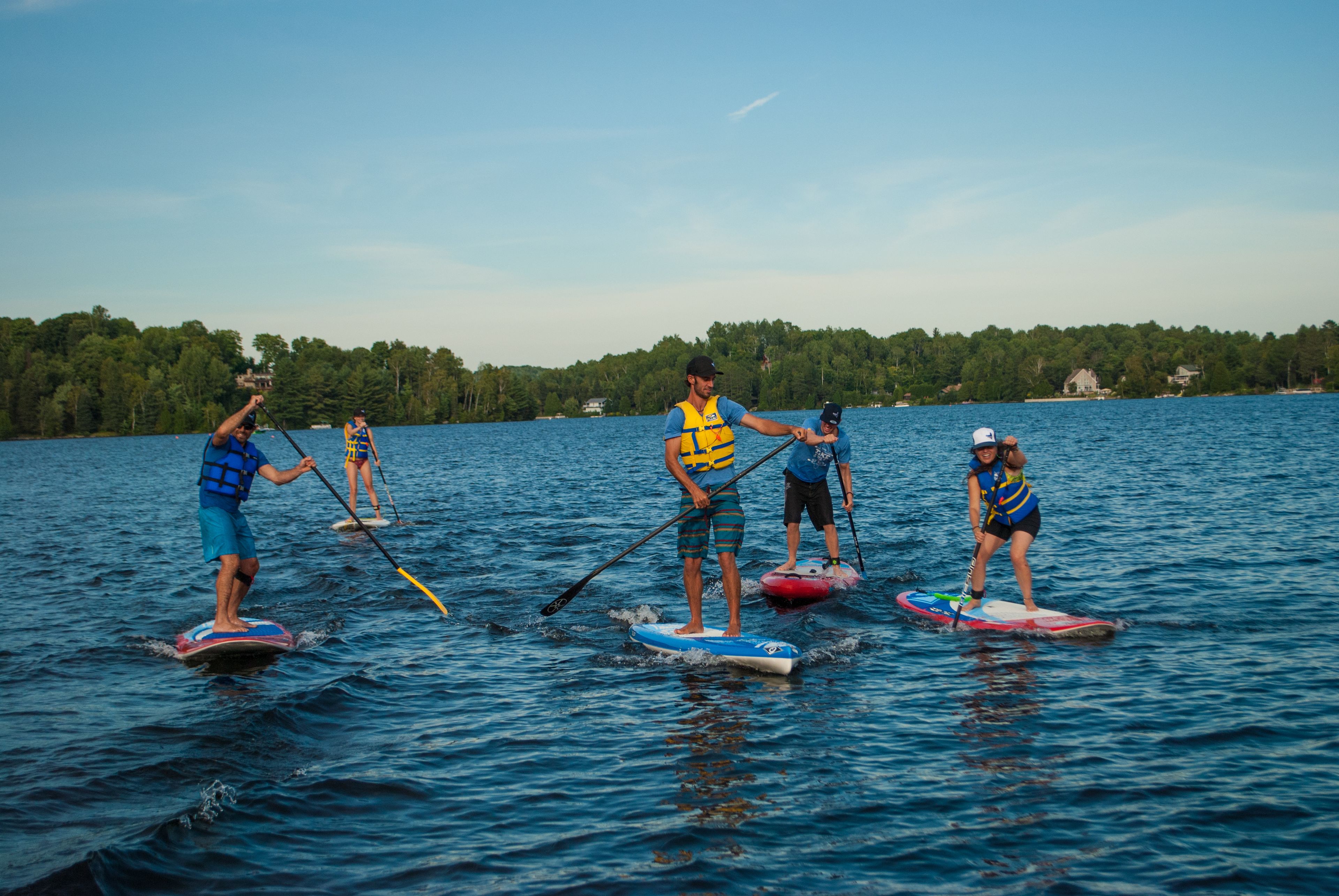 Un grupo de personas haciendo paddleboard en un lago tranquilo, con árboles al fondo.