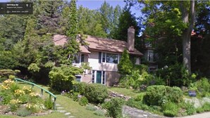 A residential house with a front yard, a stone wall, and a street view. - Niagara Riverview Inn (Niagara Falls)