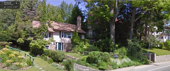 A residential house with a front yard, a stone wall, and a street view. - Niagara Riverview Inn (Niagara Falls)