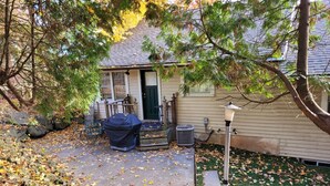 A house with a covered grill, a porch with a table and chairs, and a pathway leading to the entrance. - Niagara Riverview Inn (Niagara Falls)