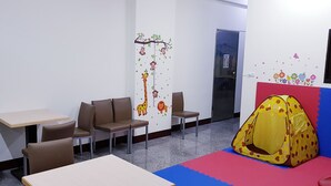 Una sala de juegos infantil con una carpa, sillas, mesas y decoraciones educativas en la pared.