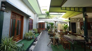 Un patio con zona de comedor, plantas en macetas y un área de estar techada.