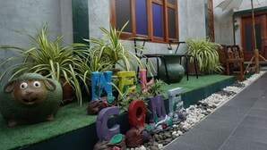 Un espacio exterior decorado con plantas en macetas, una mesa de madera y una silla.