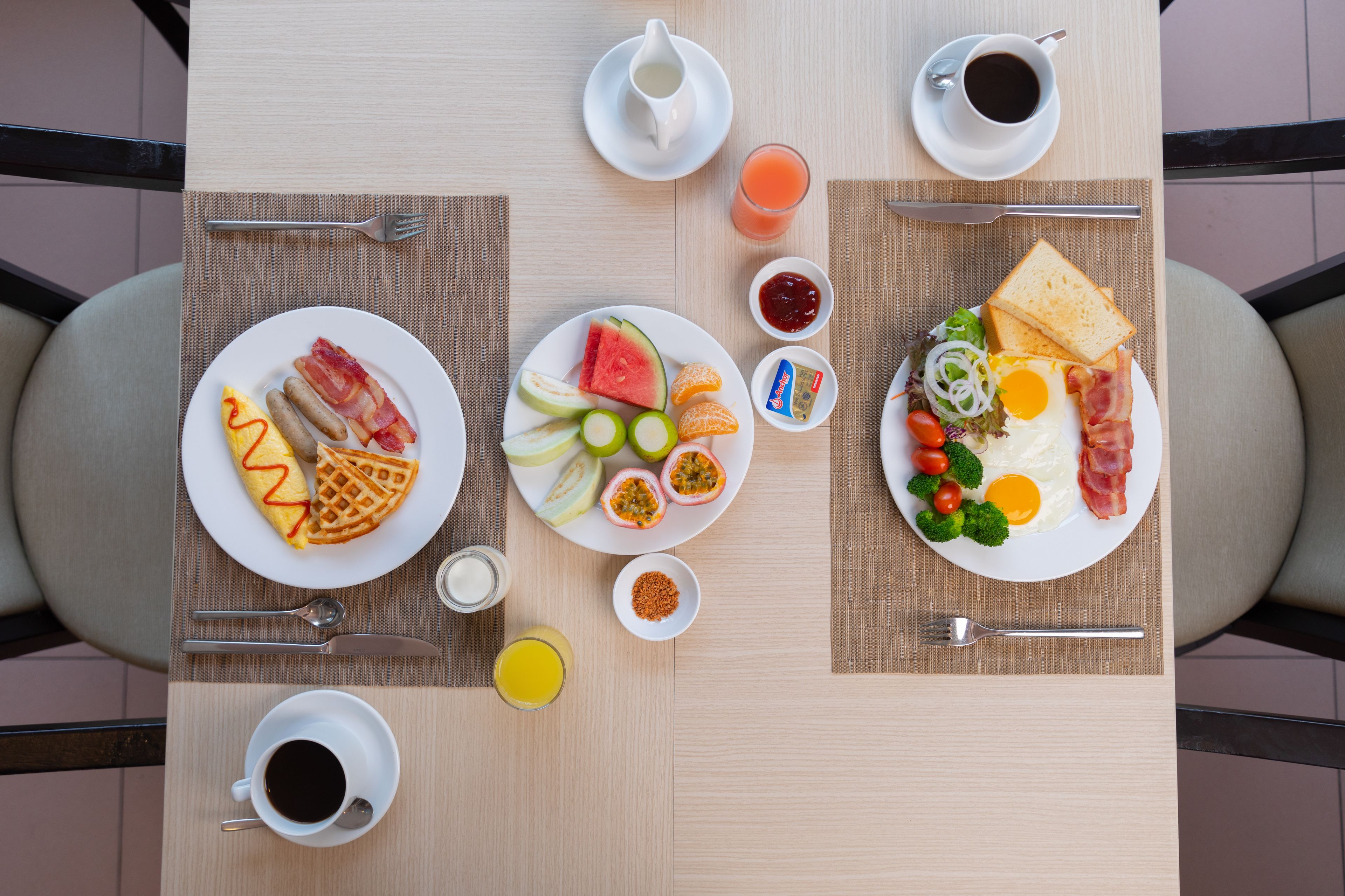 A breakfast table with plates of food, cups of coffee, and a glass of orange juice.