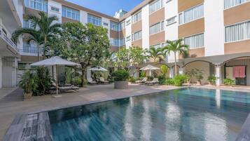 Una piscina al aire libre, sombrillas, sillones reclinables de piscina