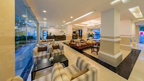 Un hall d’hôtel moderne avec un comptoir d’accueil, un espace salon et une vue sur l’extérieur.