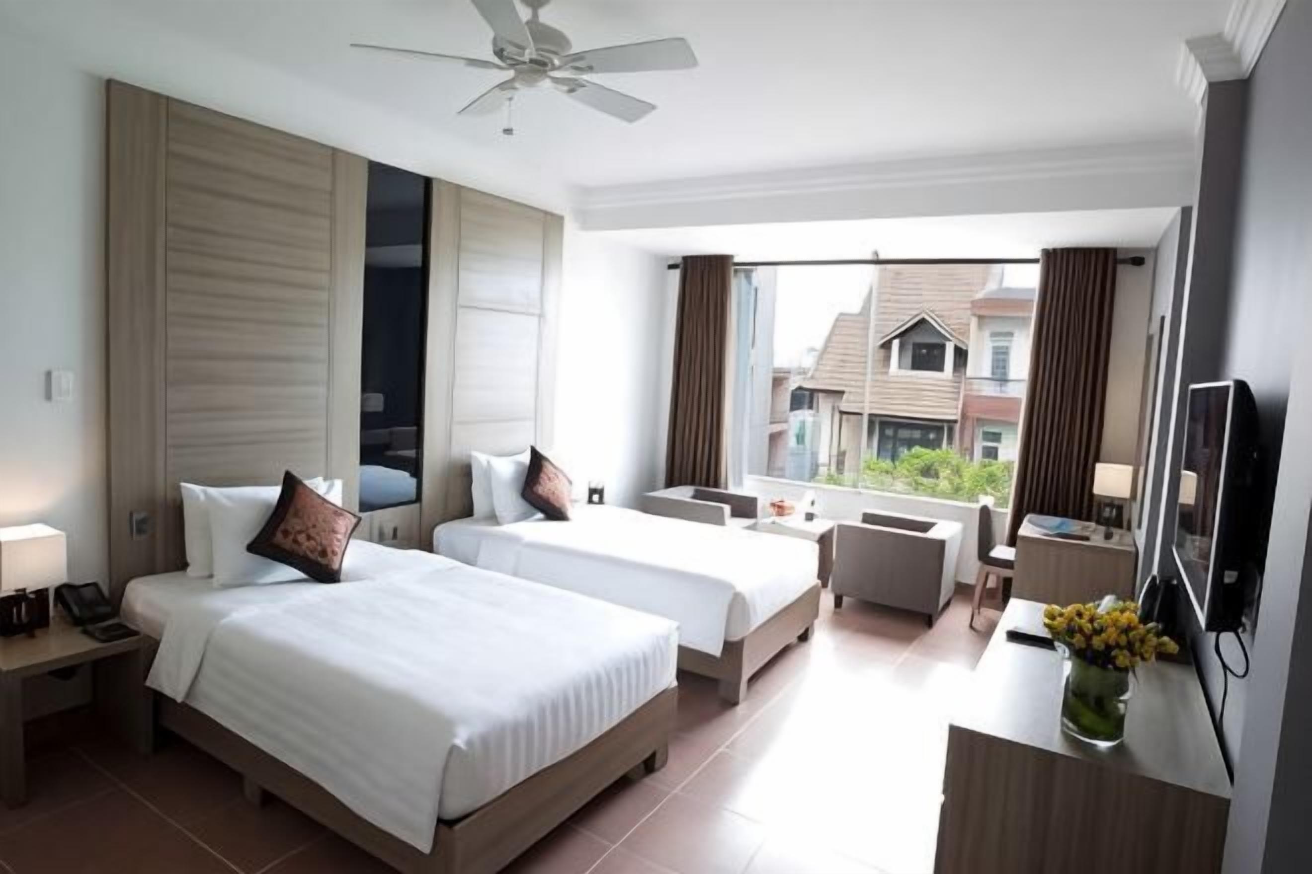 Une chambre d’hôtel avec deux lits, un bureau, une chaise, une télévision et un balcon avec vue.