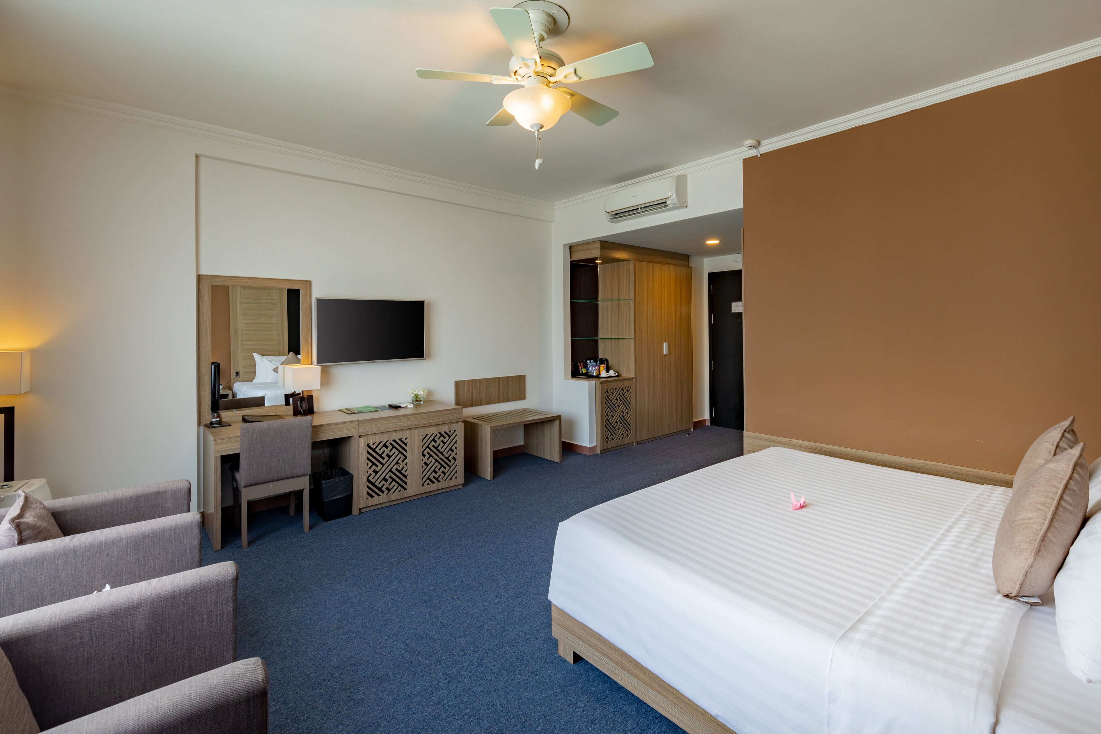 A hotel room with a bed, a desk, a chair, a television, and a wardrobe.