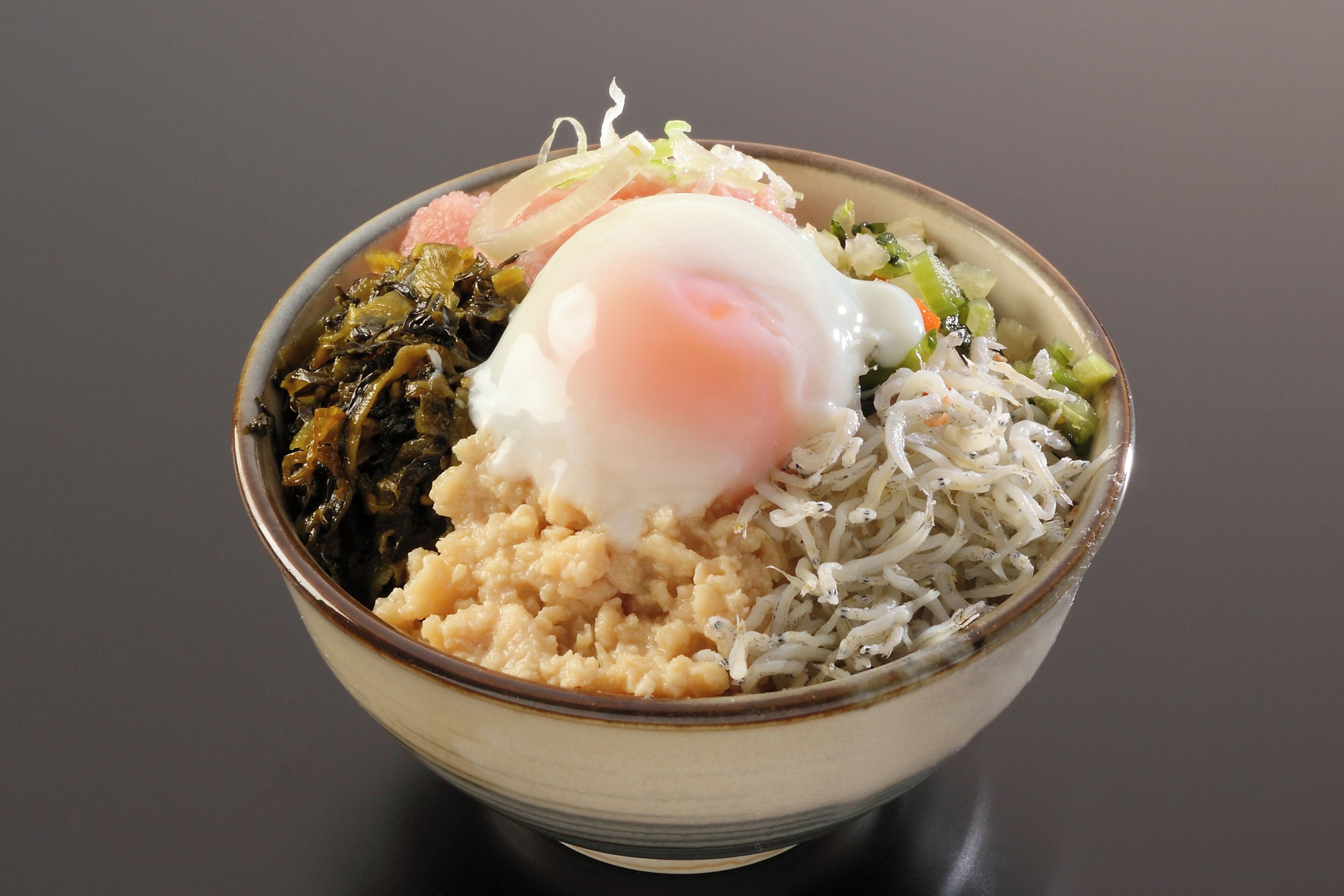 A bowl of food with a poached egg, rice, and vegetables.