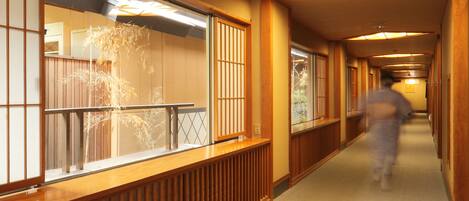 A corridor with wooden paneling, a glass railing, and a person walking.