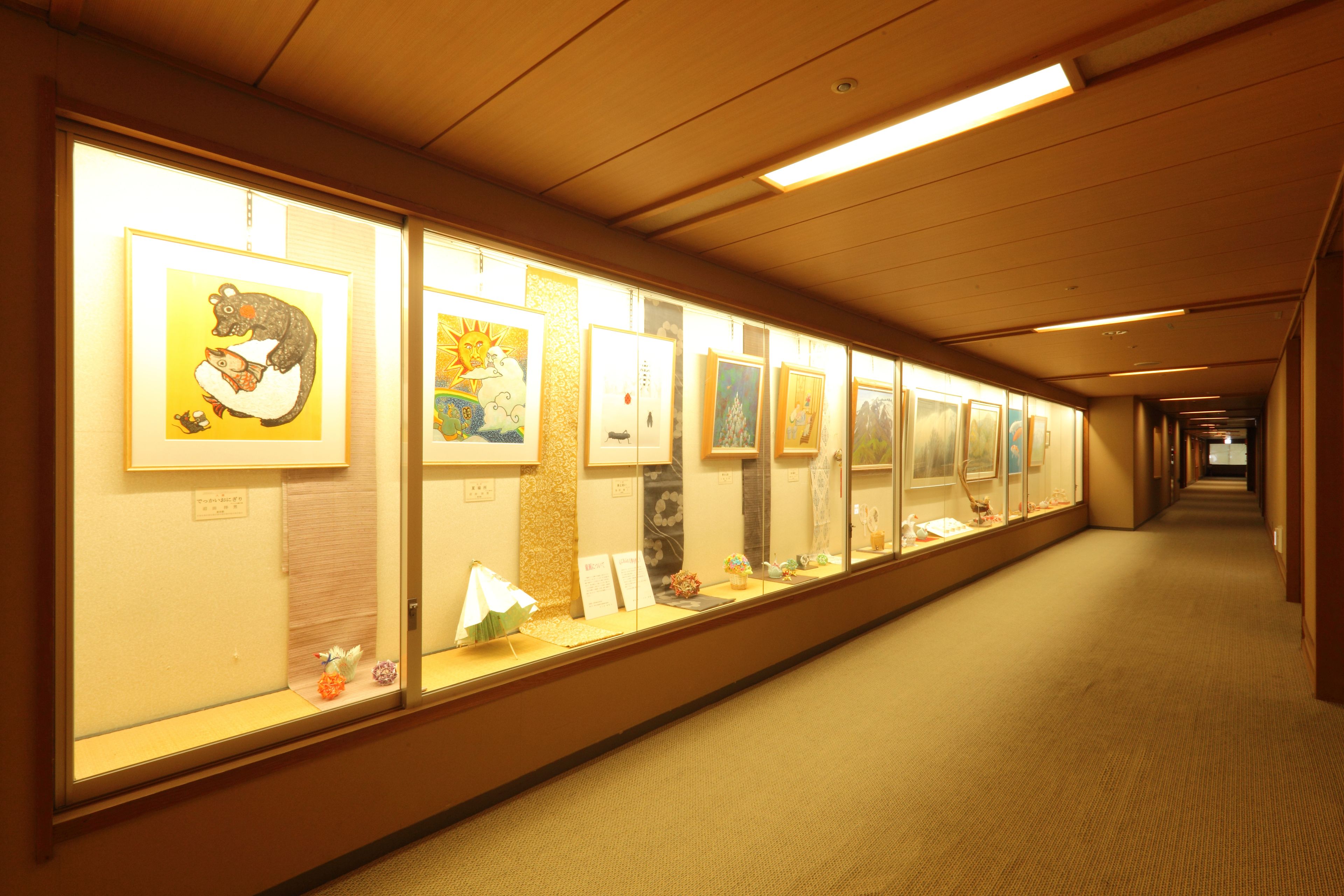 A hallway with framed artwork on display, carpeted floors, and overhead lighting.